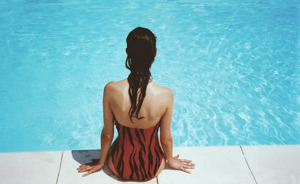 chica sentada y con los pies dentro de la piscina